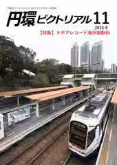 複数並んだ駅のホームの一つに横長のマギレコポスターが掲出されており、隣の線路には路面電車が停車している写真