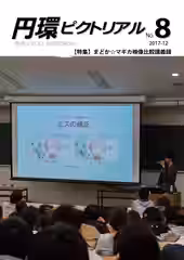 教室のスクリーンにスライドを映しながらマイクを持って説明している写真